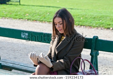 Beautiful young woman reading outside on a bench on a sunny autumn day