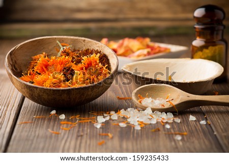 Homeopathic medicine, calendula dry flowers and wooden surface.