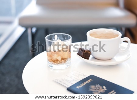 Coffee, dessert and passport on white table in business lounge zone in airport. 
