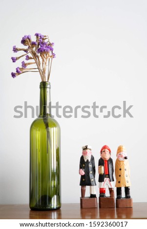 Wooden sailor carved figures next to wine bottle with flowers
