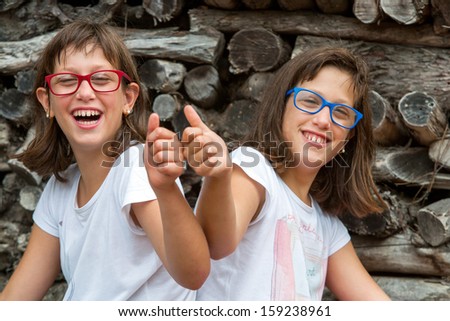 Portrait of two handicapped twin sisters doing thumbs up.