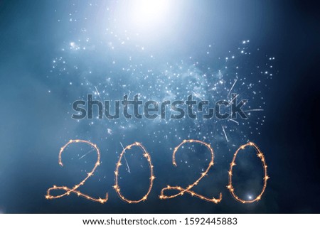 New Year 2020 celebration. Magic holiday background with fireworks. Number 2020 written sparkling sparklers.