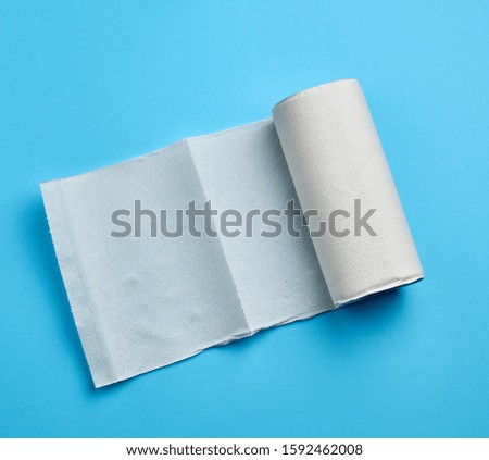 twisted roll of white paper towel on a blue background. Paper sheet. Household equipment. White napkin.
