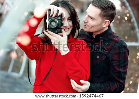 Happy couple taking photos of each other walking in a city selfie with camera. Man teaching a woman photography.