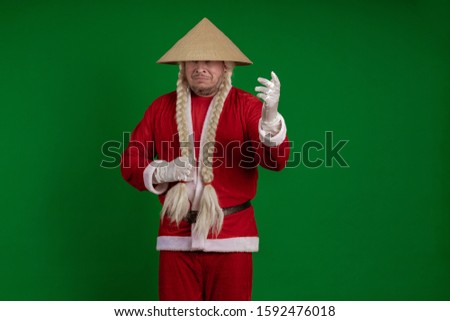 Emotional Santa Claus with long braids hairstyle and Asian hat posing on green chrome background