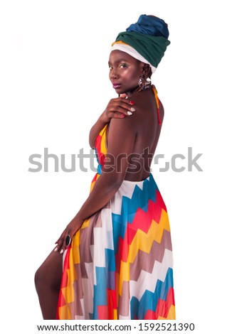 Studio fashion portrait of young African ethnicity woman in summer colorful dress and ethnic head wrap. Isolated white background.