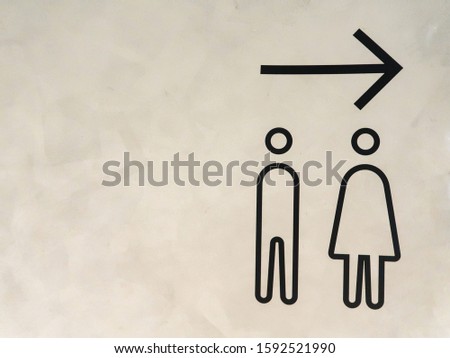 sign of the way to the restroom of male and female on gary cement wall. drawing symbolic of man and woman and arrow on cement scene.                               