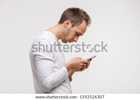 Close up portrait of man looking and using smart phone with scoliosis, side view, isolated on gray background. Rachiocampsis, kyphosis curvature of neck, Incorrect posture, , 
orthopedics concept Royalty-Free Stock Photo #1592526307