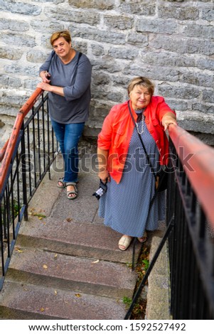 Two Mature plump women walk around the old town and are photographed against the background of an ancient castle.  Tallinn, Estonia