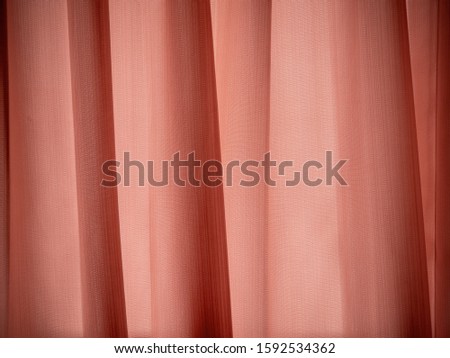 Close up blind or curtain surface, Old-rose or light orange color fabric with texture light and shade on window backdrop. Curtain soft pleated pattern.