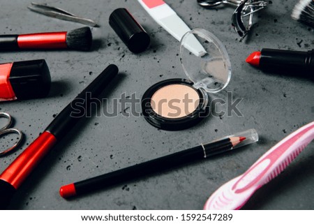 A set of cosmetics on a dark stone background. The concept of doing makeup, caring for the appearance of women. Applying brushes, eye shadows, powder.