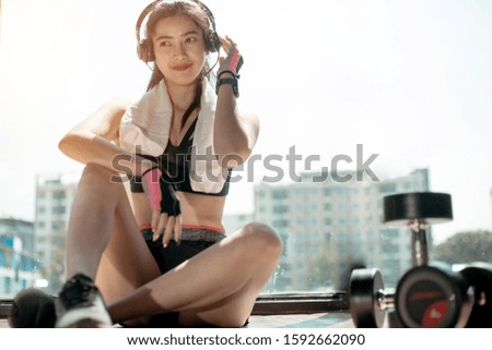 Woman exercise workout in gym fitness breaking relax listen to music after training sport with dumbbell and lifestyle bodybuilding.