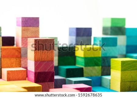 The building blocks. Spectrum of stacked multi-colored wooden blocks with white space above. Background or cover for something growing, rising, increasing, or building up.