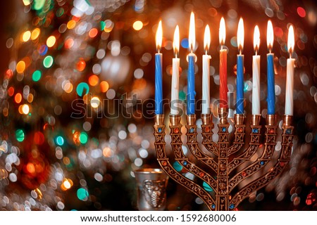 Burning candles with menorah for Hanukkah on defocus color lights background. Jewish holiday