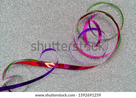 Multicolored shiny serpentine ribbon on a silver background