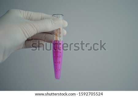 close-up hand holding test tube with purple pink liquid, copy space