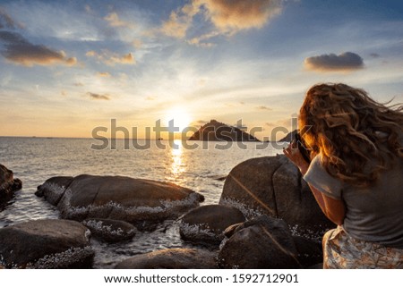 Women taking picture of island by sunset