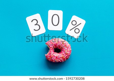 30% off discount - sale concept with bitten donut - on blue background top-down copy space