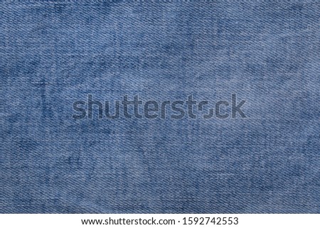 Close-up of bright blue denim jeans as background. Top view with copy space. Denim background texture for design. Canvas denim texture.