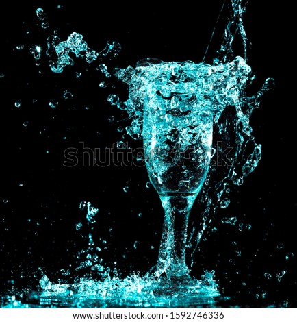 blue water with splashes in a glass on a black background.