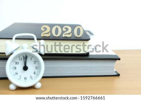 Concept for happy new year 2020 wooden number with clock and book on a table