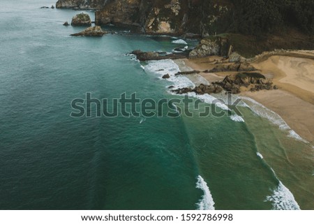 Aerial view of surfers and waves in a rocky coastline, drone shot