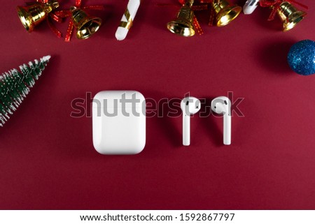 christmas headphones. Air Pods. with Wireless Charging Case. New Airpods 2020 on red background. Air Pods on Christmas background.
