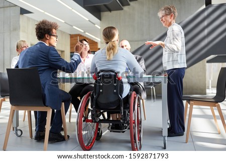 Group of business people in a meeting with colleague in a wheelchair for inclusion Royalty-Free Stock Photo #1592871793