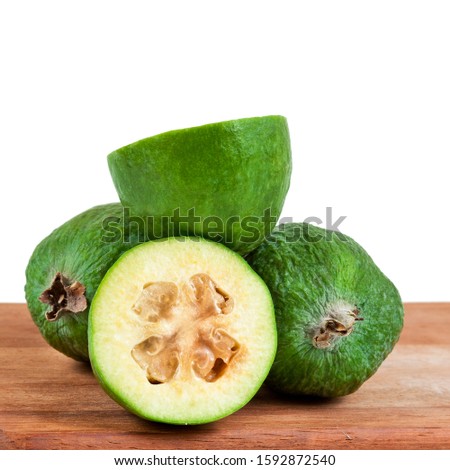 Fresh feijoa fruits (acca sellowiana, pineapple guava) on a wooden desk isolated on a white background.