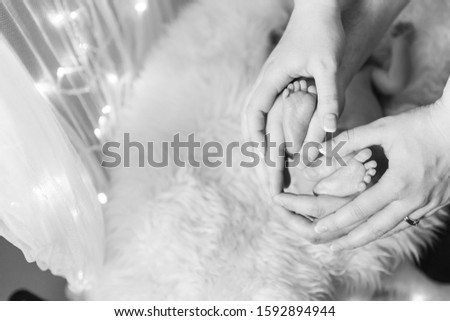 Parents hands holding their newborn feet in their hands and building a heart around them