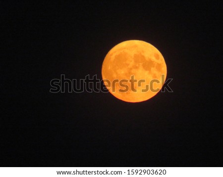 Black background with moon silhouette. The bright disk of the earth's satellite in the dark night sky. The full moon in the clouds, phases of the lunar Eclipse