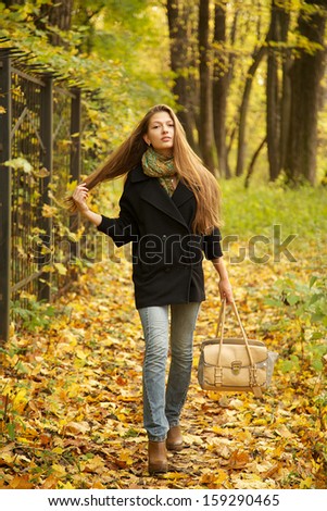 girl walks on leaves in autumn park