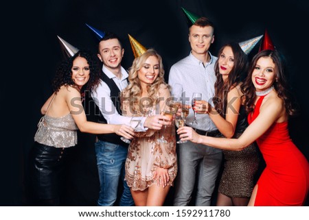 Friends birthday party. Six people having fun and drinking champagne on black background