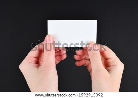 Empty card in woman hand  on a black background. Copy space. 