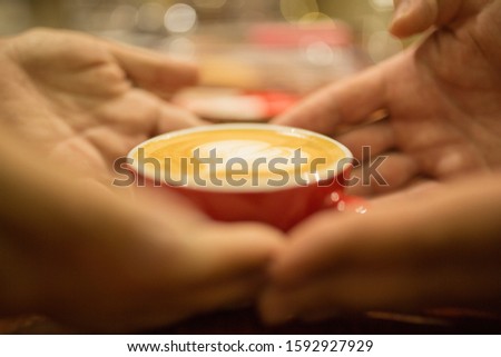 male and female hands are holding a cup of coffee