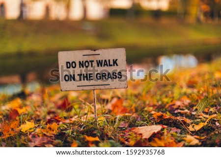 do not walking on the grass. prohibition sign on lawn in autumn park