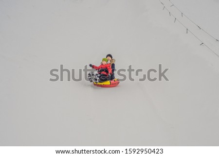 mom son ride on an inflatable winter sled tubing. Winter fun for the whole family
