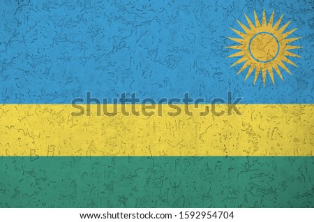 Rwanda flag depicted in bright paint colors on old relief plastering wall. Textured banner on rough background