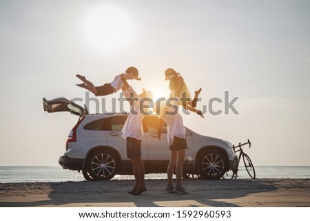 Family vacation holiday, Silhouette of the happy family on the evening beach. Father and mother are happily carrying their son and daughter on the beach, Car and bicycles in the back.