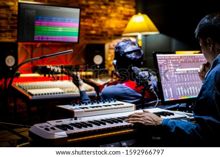 professional male music producer, composer working with guitarist in recording studio. music production concept