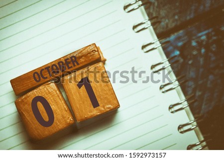 october 1st. Day 1 of month, Handmade wood cube with date month and day placed on a lined notebook on a blue background. artistic coloring.  autumn month, day of the year concept