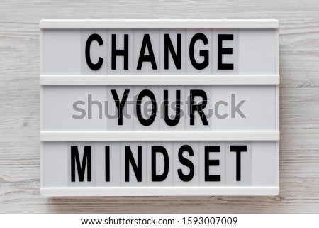 Overhead view, 'Change your mindset' words on a lightbox on a white wooden background. From above, flat lay, top view.