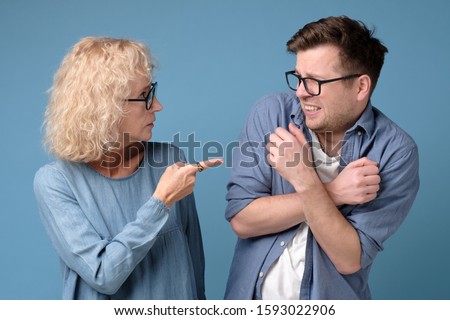 Angry mature woman shouting, blaming millennial annoyed son in eyeglasses. Generation problems. Studio shot Royalty-Free Stock Photo #1593022906