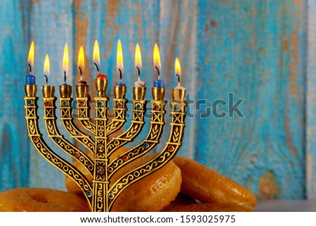 Traditional jewish dish sweet donuts with burning candles on minorah.