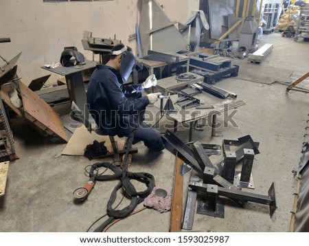 Metal workers use manual labor, Skilled welder, Factory workers making OT, The welder is welding the steel in the factory, Welding fumes, The welder stands to weld the iron in the dark.