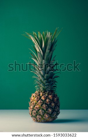 fresh ripe pineapple on a green background, minimalism concept,copy space,vertical imag,stock photography