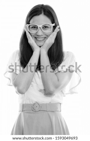Studio shot of happy young beautiful woman smiling and touching both cheeks while wearing eyeglasses