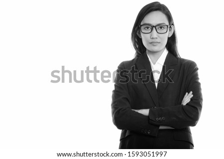 Studio shot of young Asian businesswoman wearing eyeglasses with arms crossed