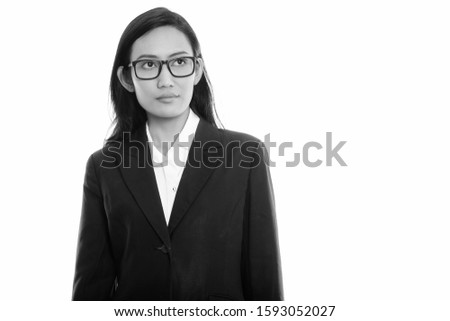 Studio shot of young Asian businesswoman thinking while looking up