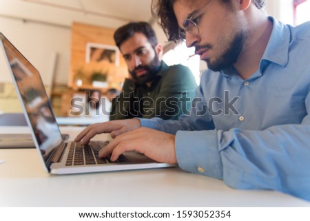 Serious focused man using laptop in office. Closeup of male employee typing on keyboard. Internet communication concept